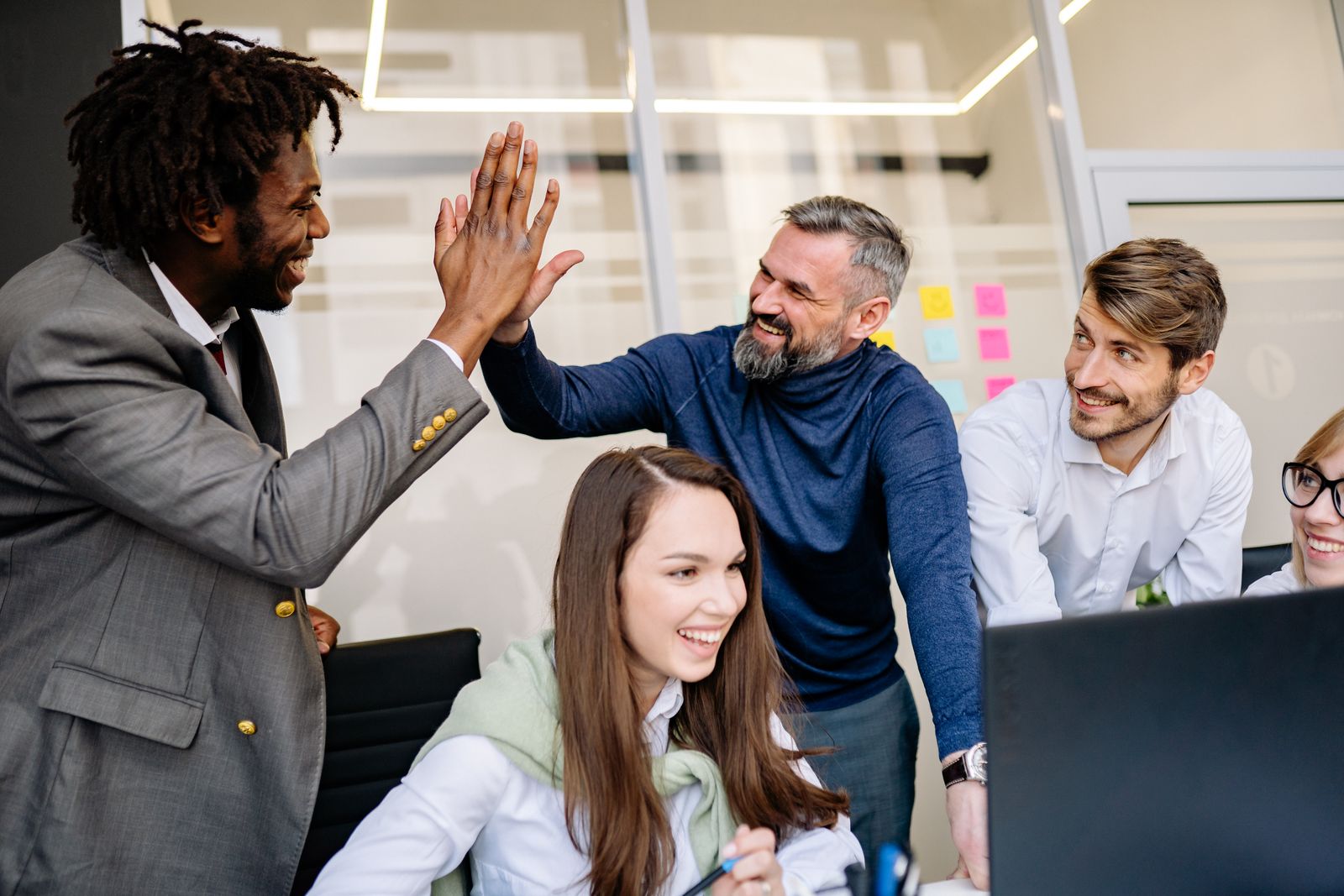 Colleagues high-fiving across a desk in an open office