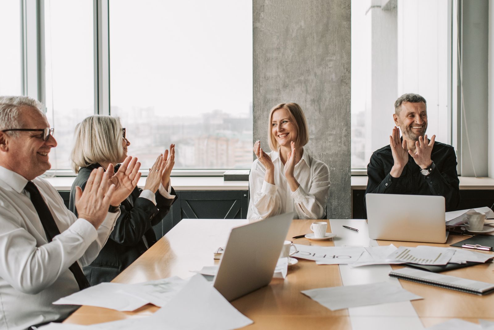 A team applauding a colleague around a conference table