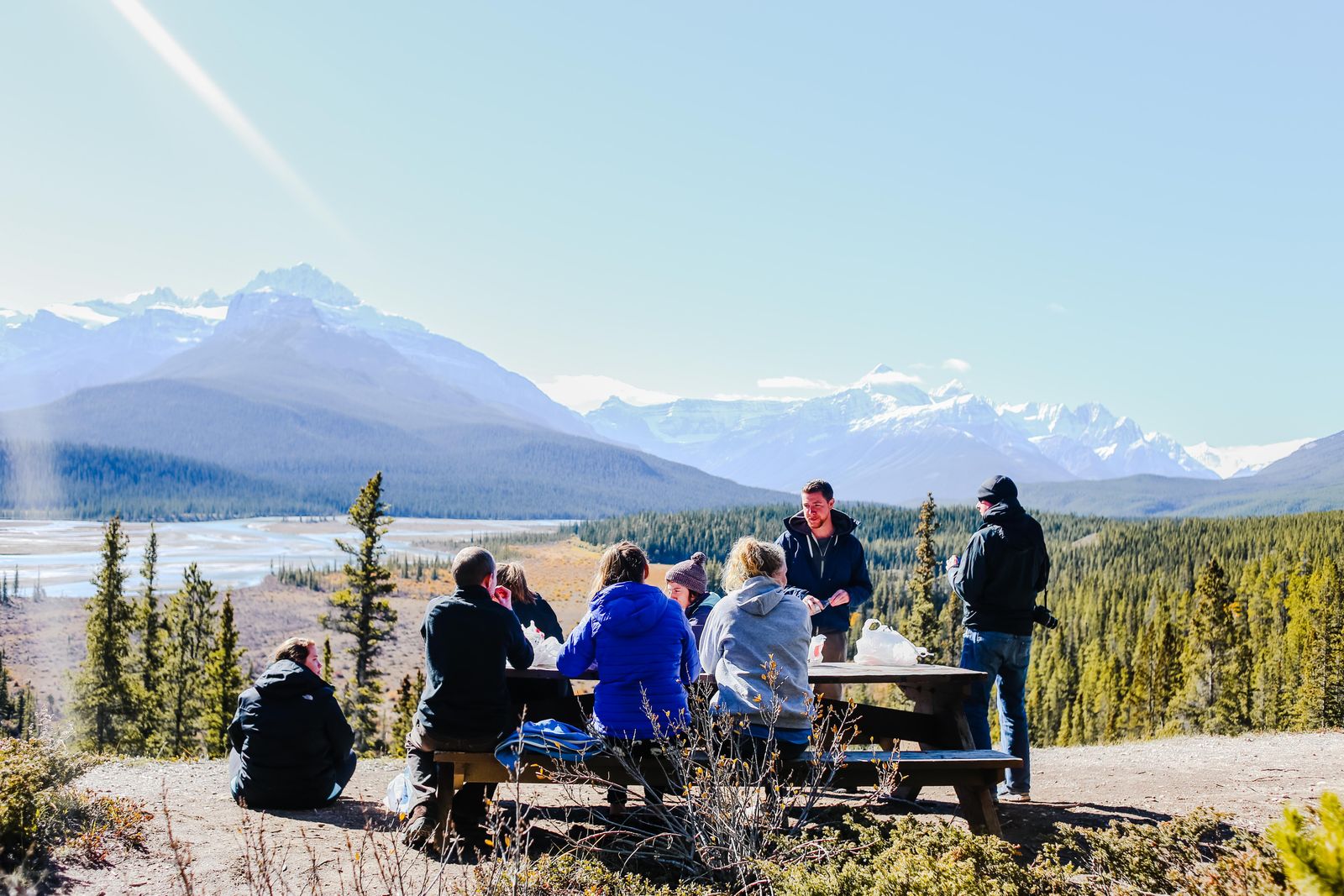 A leadership team meeting outdoors with mountains behind them