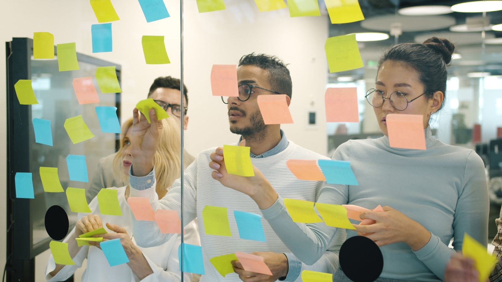 Colleagues working through ideas on sticky notes together